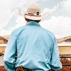 Person wearing a light blue shirt and cowboy hat with American branding, standing in an outdoor setting.